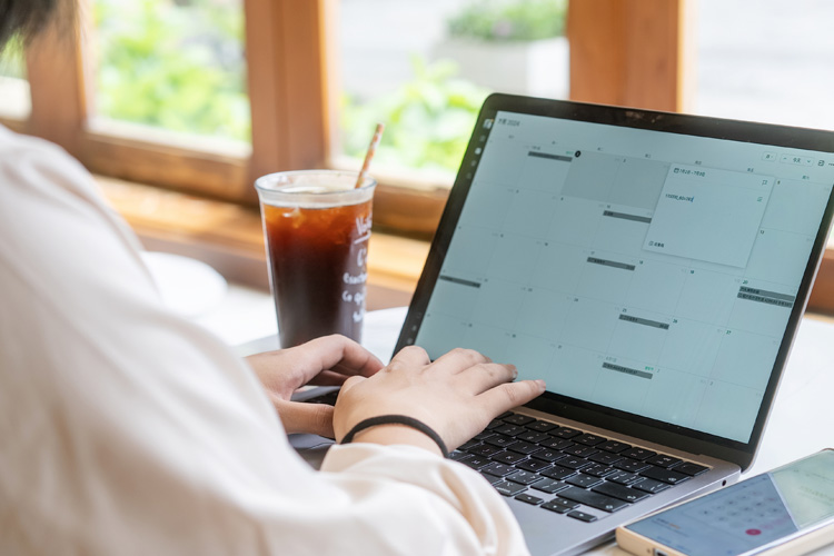 Working women manage calendars on the computer.