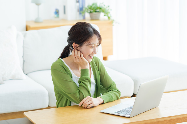 A young woman looking at a laptop in the living room.